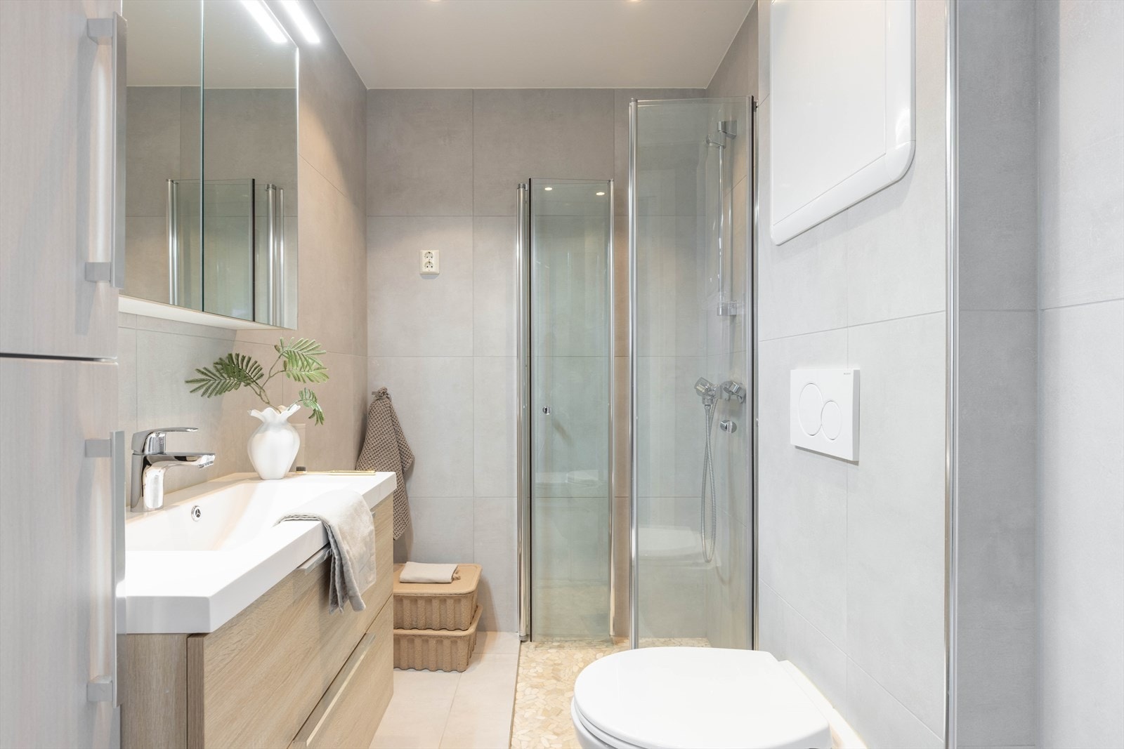 Det er lekkert innredet med baderomsmøbel med slette fronter, heldekkende servant og ett-greps blandebatteri. Det er speilskap med belysning og dusj med innfellbare dører i herdet glass, samt dusjgarnityr med hånddusj. Galleribilde