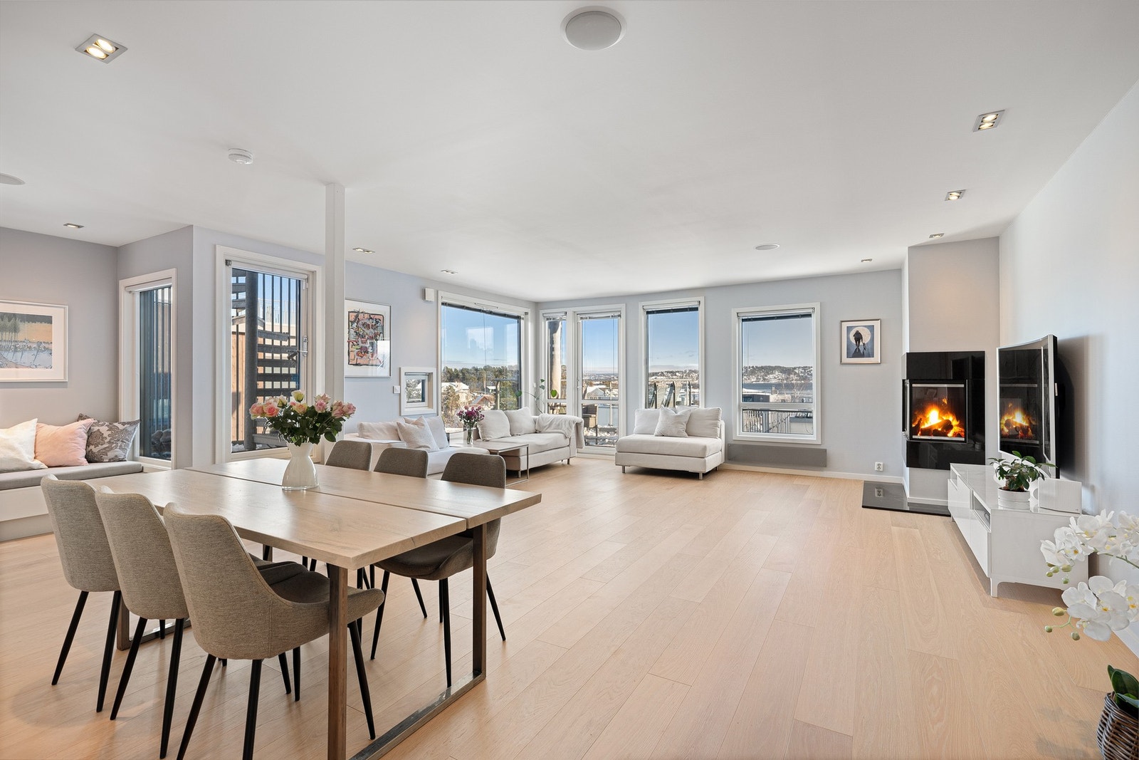 Lys og lekker stue og spisestue i åpen løsning med peis. Store vindusflater skaper en ekstra luftig romfølelse og rammer inn en spektakulær utsikt over Oslofjorden. Galleribilde