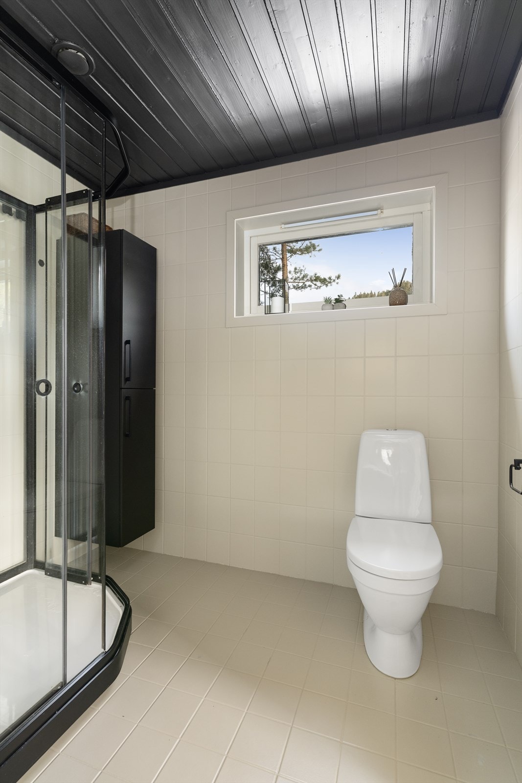 Badet er malt opp i en delikat beige tone med flis på gulv med varmekabler, flis på vegg og mørk malt himling som står i stil med innredningen. Galleribilde