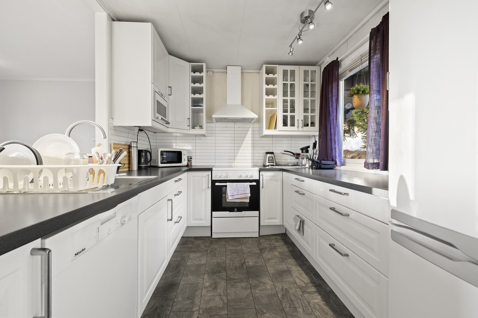 Praktisk U-formet kjøkkeninnredning med profilerte fronter og godt med skap- og benkeplass. Galleribilde