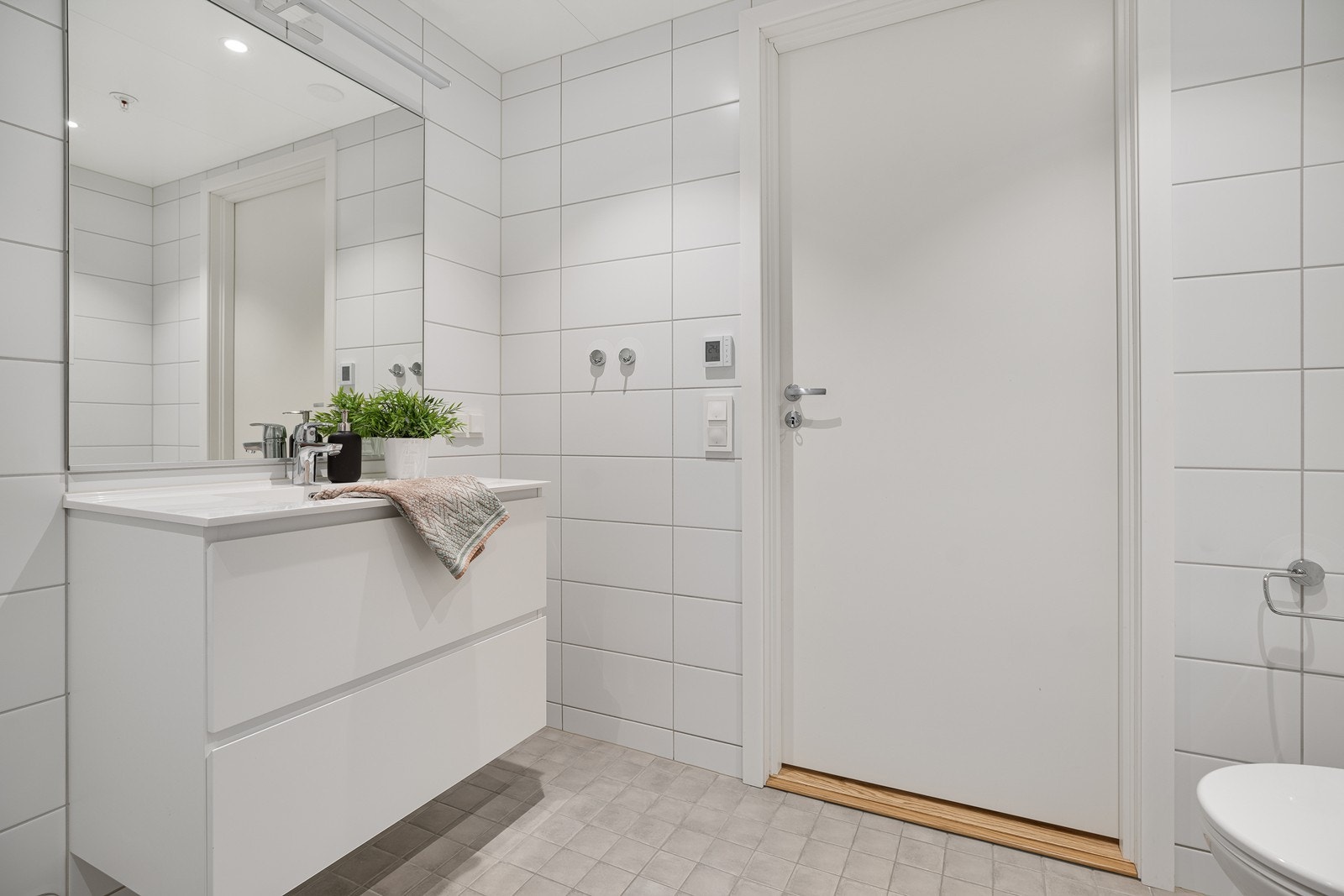 Badet er innredet med nedfelt servant, vegghengt toalett, dusjhjørne og opplegg for vaskemaskin Galleribilde