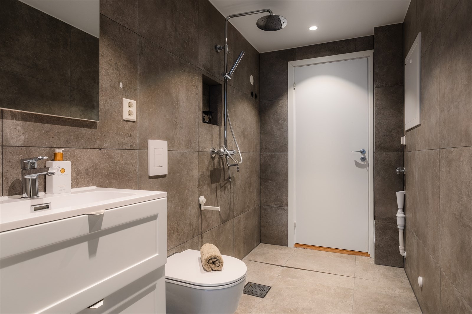 Bad 2 er like tidløst, med stilrene grå fliser på både vegger og gulv, samt innfelte downlights. Galleribilde