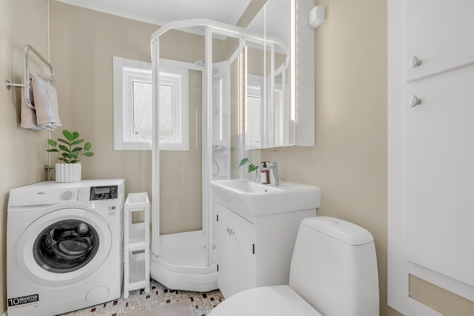 Badet er praktisk innredet med dusjkabinett og opplegg for vaskemaskin. Galleribilde