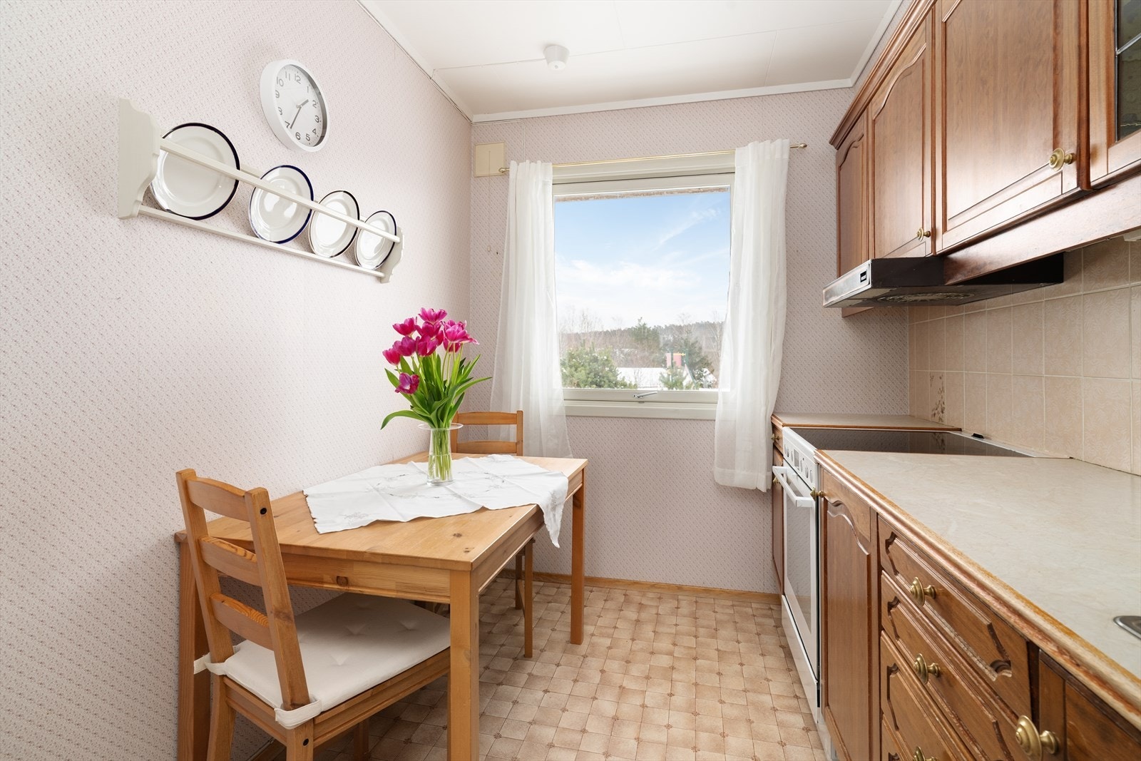 Kjøkkeninnredningen har profilerte fronter med innslag av overskap med blyglass, samt laminert benkeplate med lys og flis over benk. Galleribilde