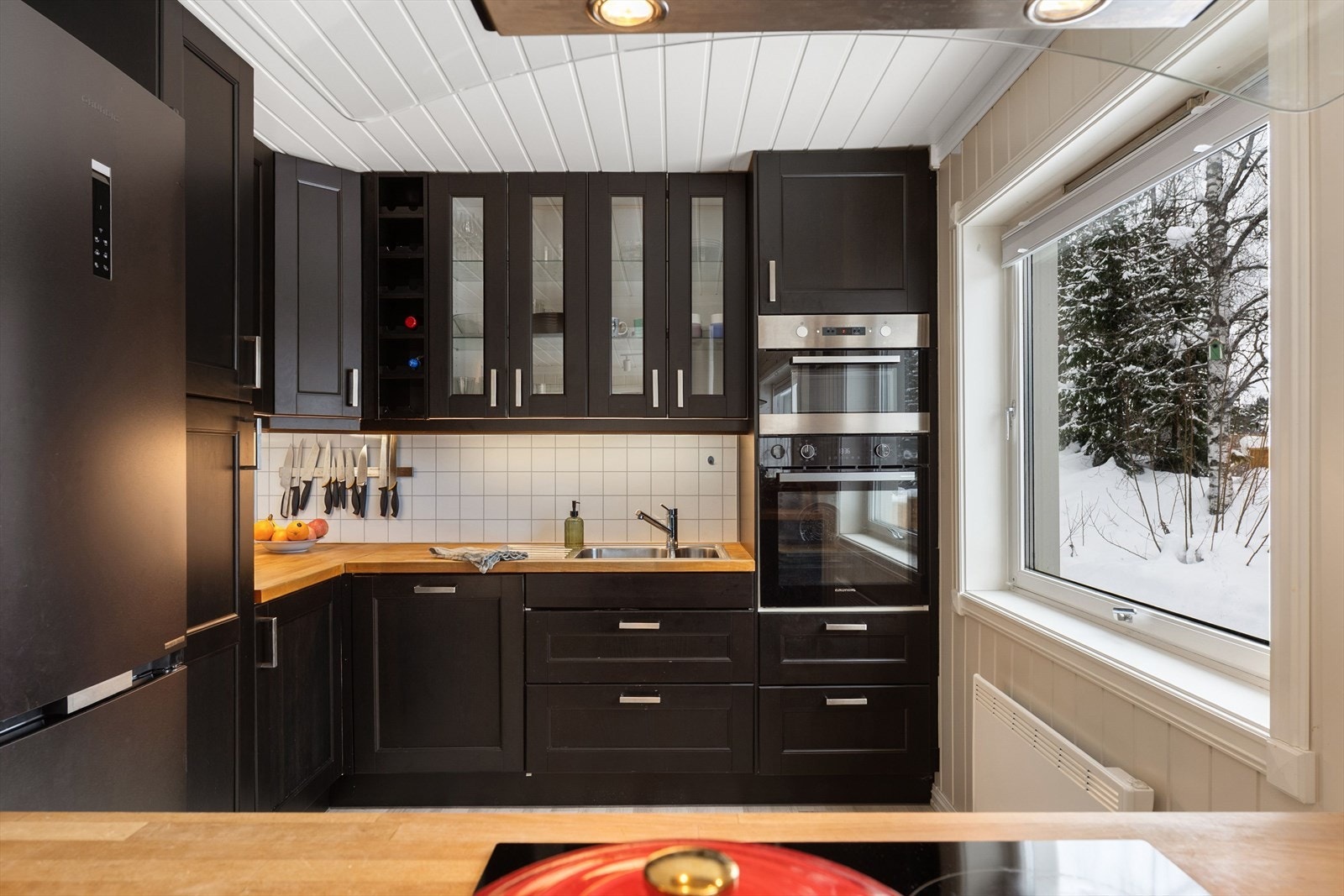 Stilrent kjøkken med mørke profilerte fronter og integrerte hvitevarer. Galleribilde