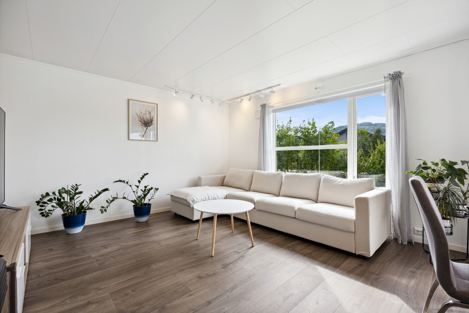 Lys stue med god plass til sofa, tv og tilhørende møblement Galleribilde