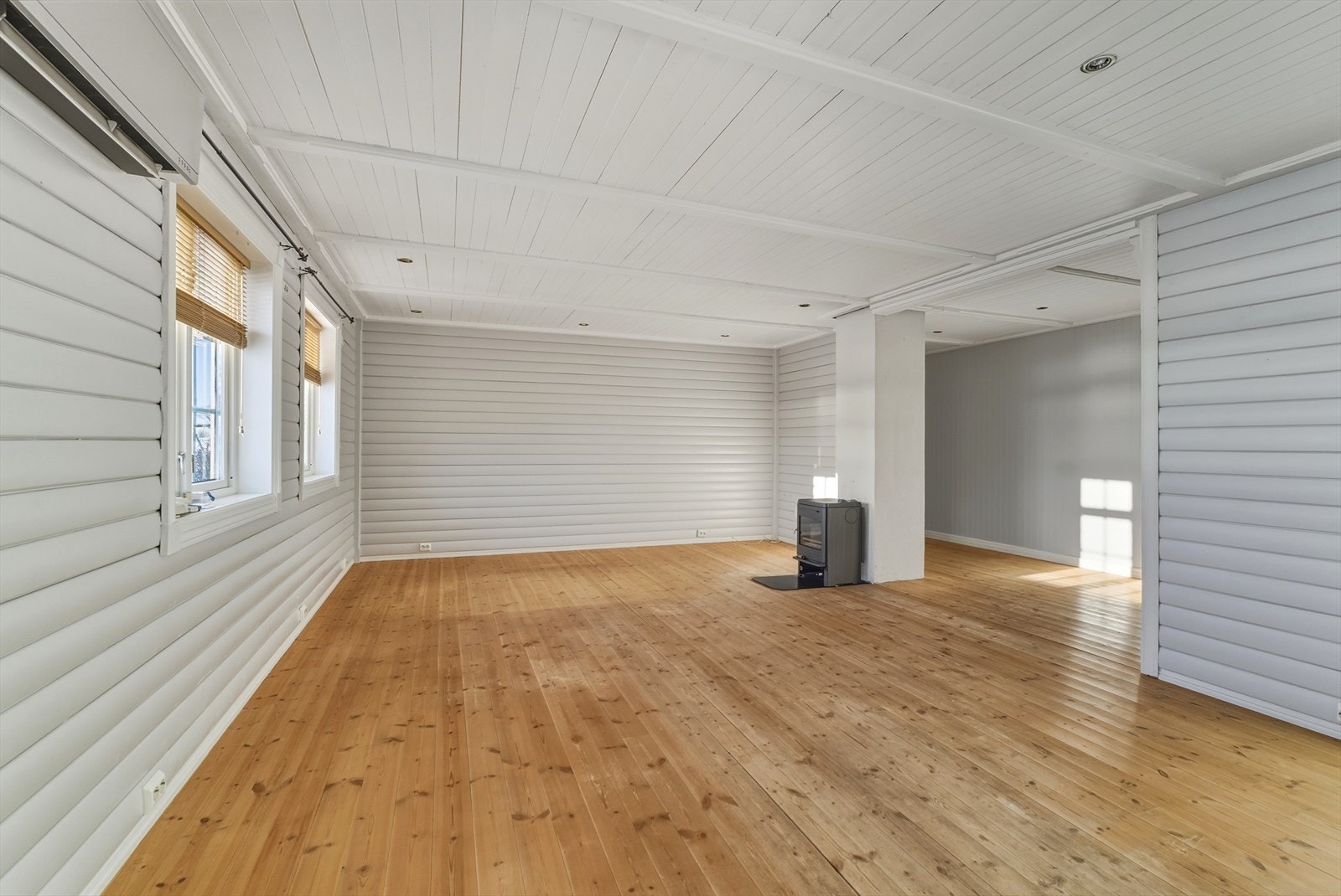 Stor og lys stue med tregulv og vedovn Galleribilde