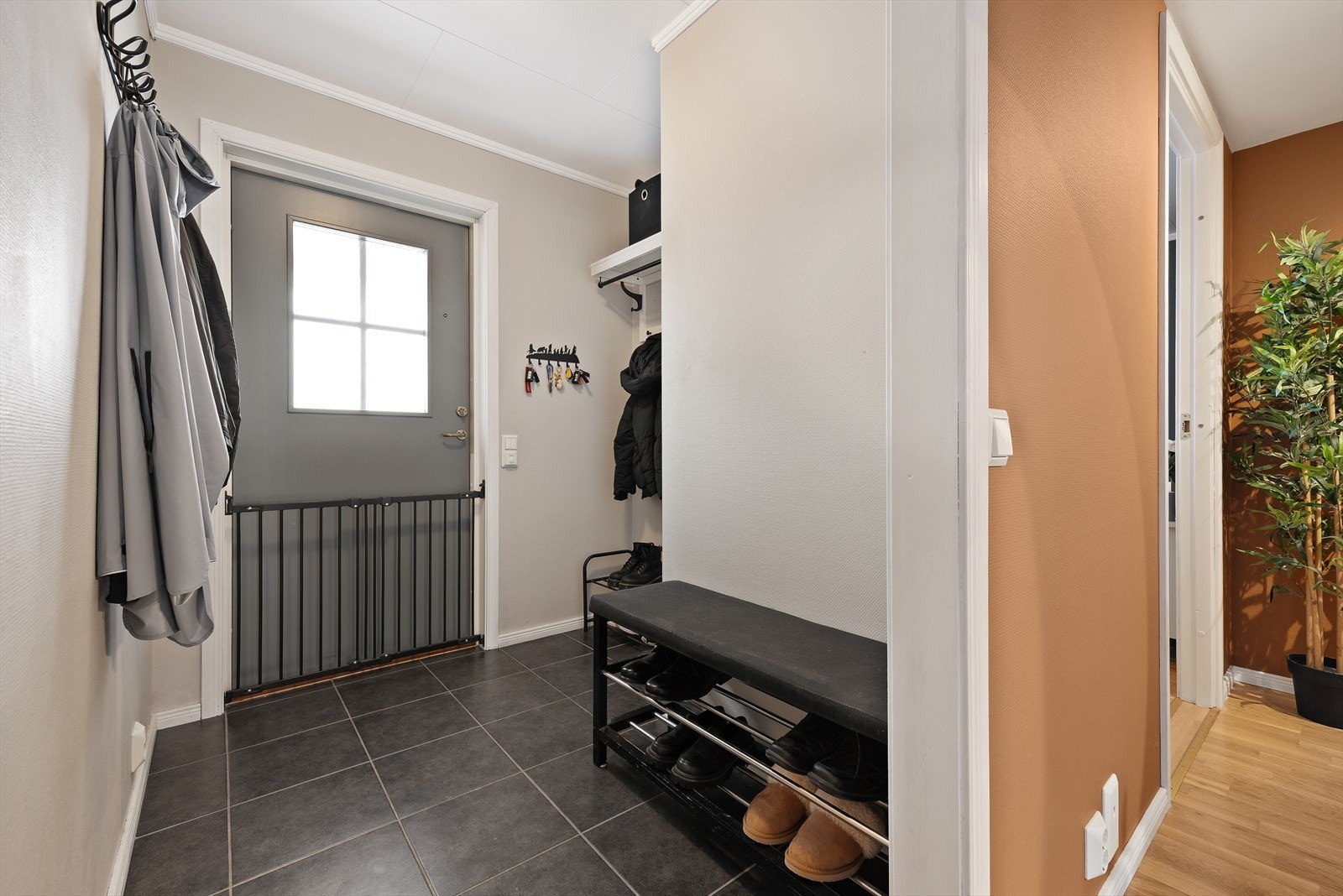 Praktisk entré med flislagt gulv, som leder videre inn i en gang. Galleribilde