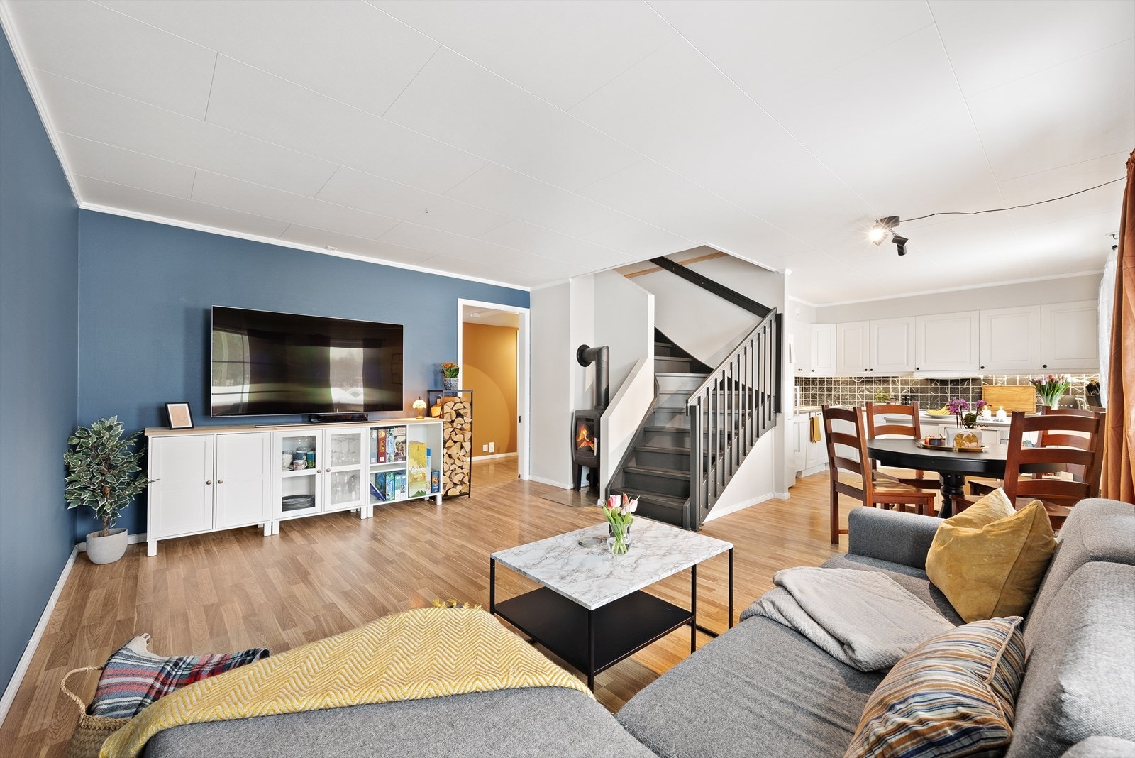 Stuen har god plass til både spisebord og sofagruppe. En vedovn bidrar med varme og hygge på kalde dager. Galleribilde