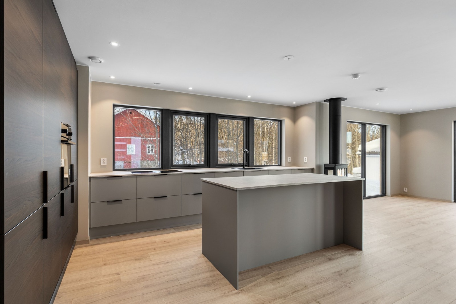 Integrerte hvitevarer inkluderer kjøleskap, oppvaskmaskin, stekeovn og induksjonstopp, noe som gir en helhetlig og ryddig fremtoning. Galleribilde