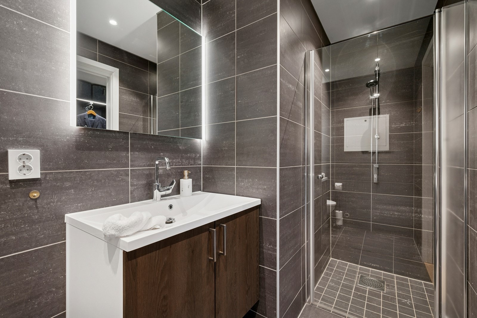 Badet er godt utstyrt med vegghengt toalett, servant og dusjhjørne. Galleribilde