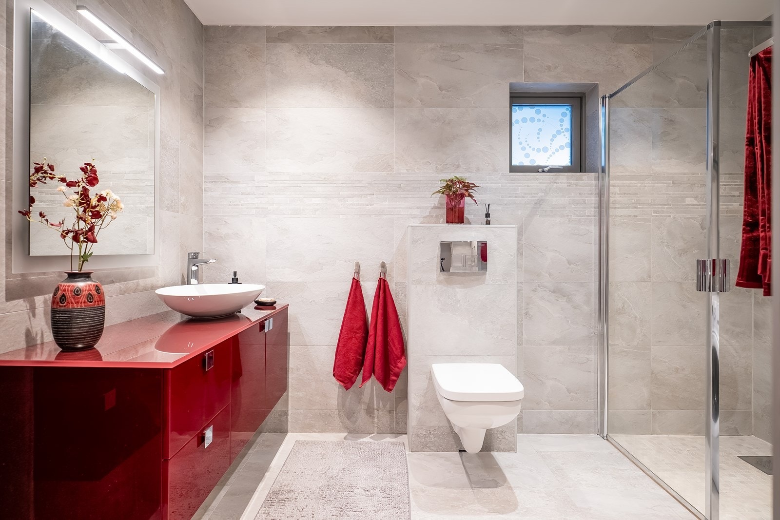 Pent og flislagt bad på hele 6m², med behagelig gulvvarme som varmekilde. Baderomsinnredningen er fra Italienske produksenten Modo 8 - fargevalg Bordeaux lucido. Galleribilde