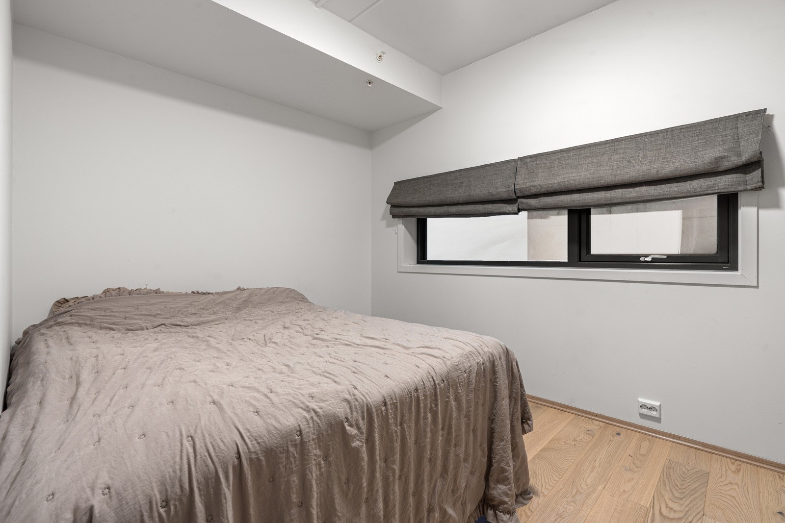 Boligens første soverom er romslig med god plass for stor seng med tilhørende nattbord.