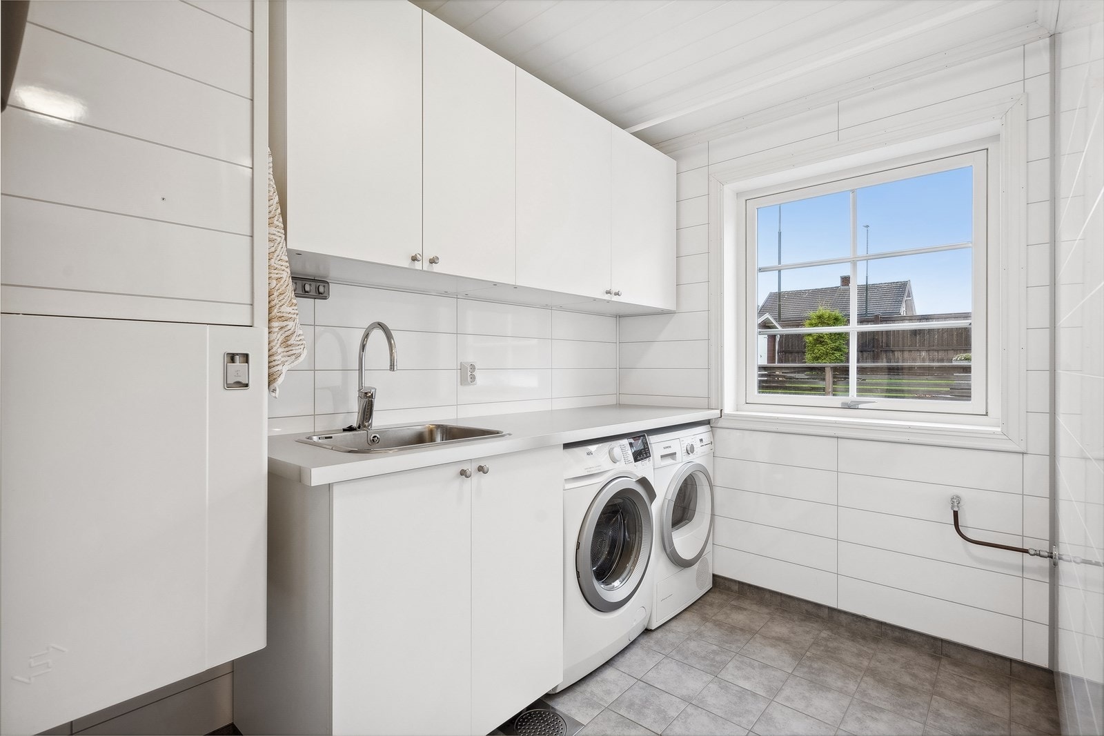 Eget og romslig vaskerom i 1.etasje med flislagt gulv og varmekabler, samt opplegg for vaskemaskin og plass til tørketrommel. Galleribilde