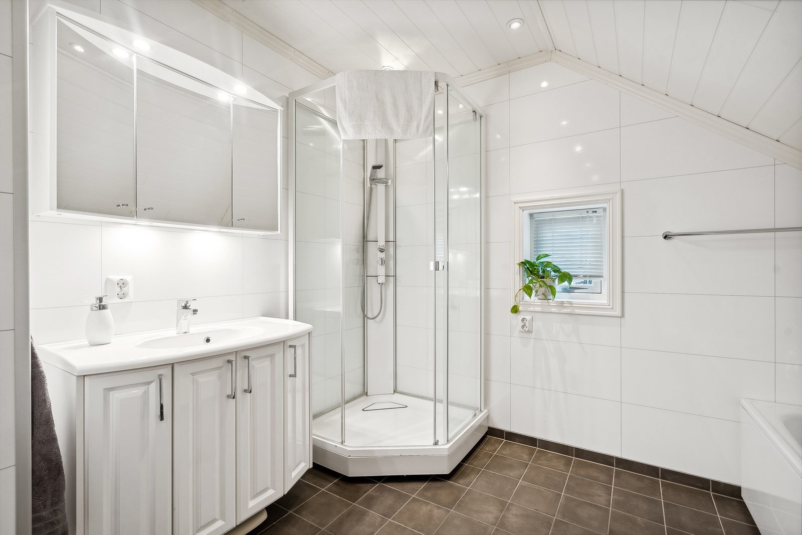 Baderommet er innredet med servant med underskap, overskap med speil og lys, dusjkabinett, vegghengt toalett og badekar. Galleribilde