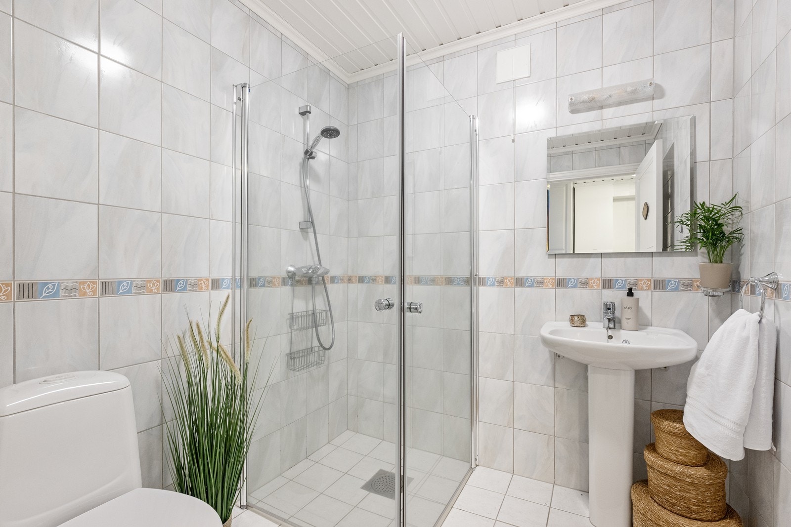 Praktisk bad i underetasjen, utstyrt med dusjhjørne med glassdører, servant og toalett. Galleribilde