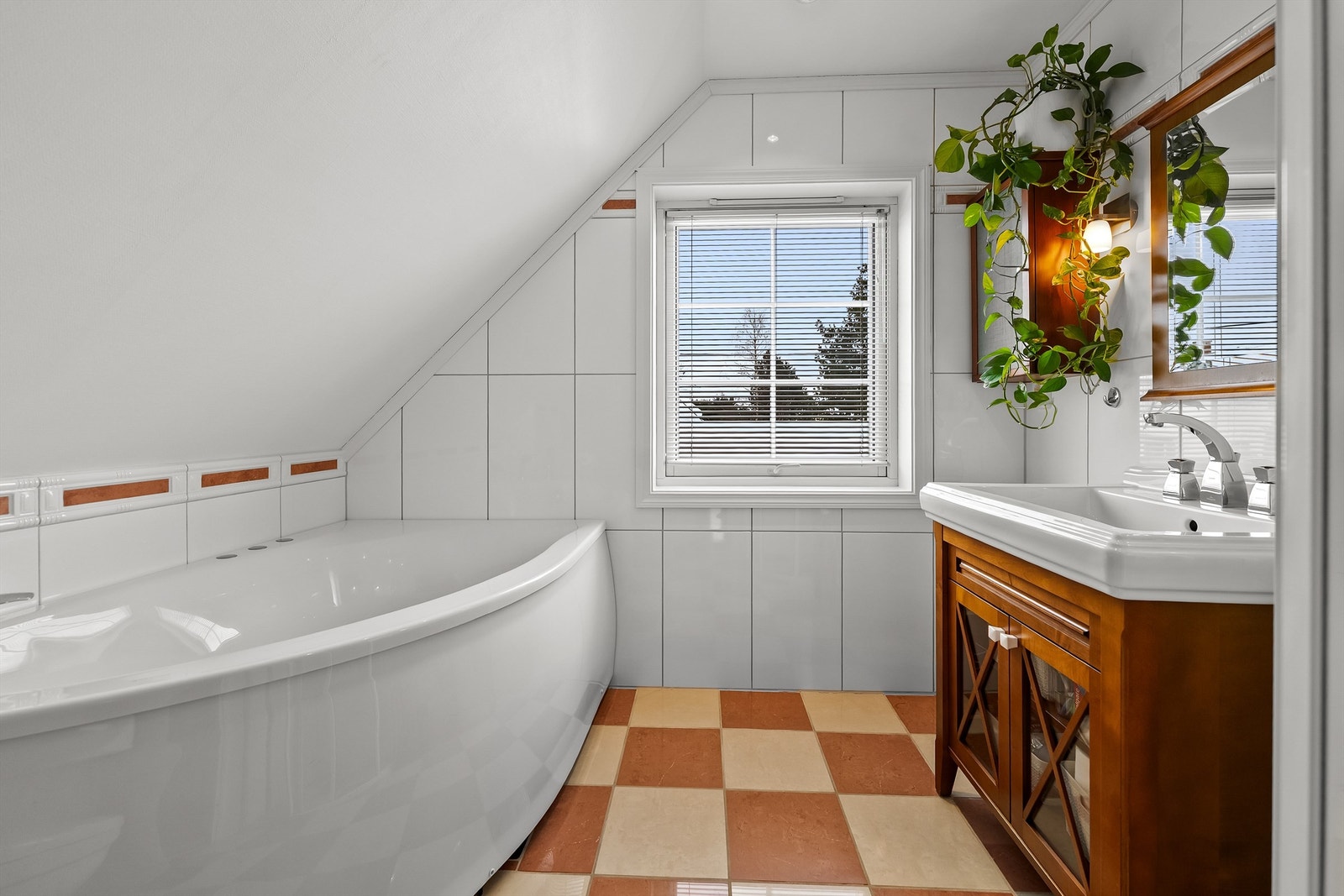 Servantskap med heldekkende servant, overskap og speil med belysning på vegg over servant, dusjnisje med glassdører og dusjarmatur, badekar med dusjarmatur, og innebygget sisterne med vegghengt toalett. Galleribilde