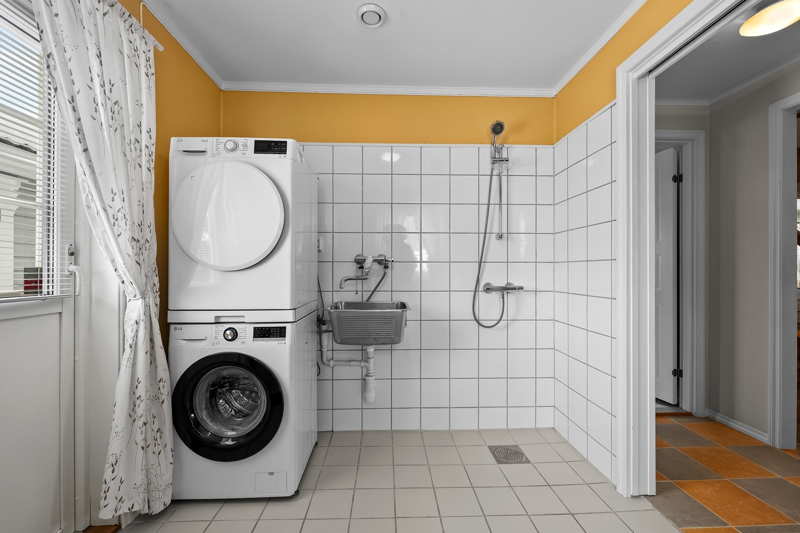 Vaskerommet har flislagt gulv med elektrisk gulvvarme, vegger i malte flater og fliser, malt himling, vegghengt utslagsvask av rustfritt stål med ett-greps armatur, dusj med dusjarmatur på vegg, og det er opplegg for vaskemaskin og tørketrommel. Galleribilde