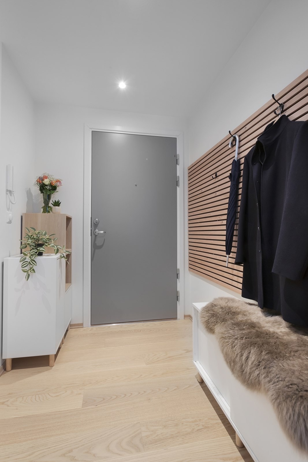 Man kommer inn i en innbydende entré med spilevegg som har knagger for oppheng Galleribilde