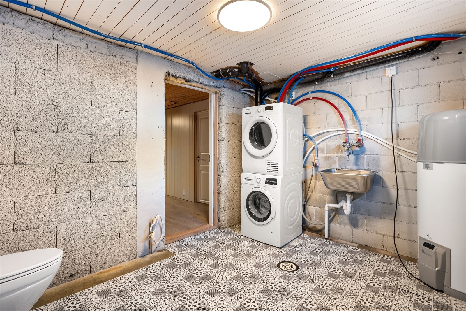 Praktisk vaskerom i kjeller med opplegg for vaskemaskin og en ny Høiax varmtvannstank fra 2026. Galleribilde