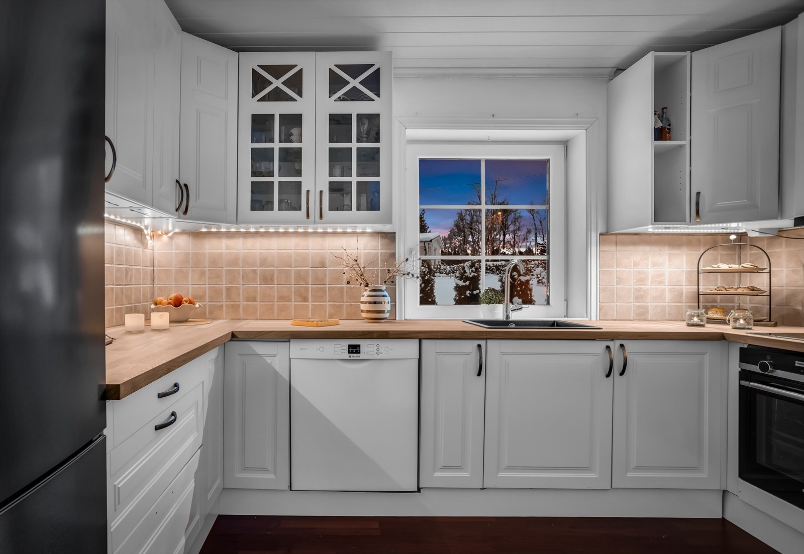 Moderne kjøkkeninnredning med profilerte hvite fronter og heltre benkeplate. Galleribilde