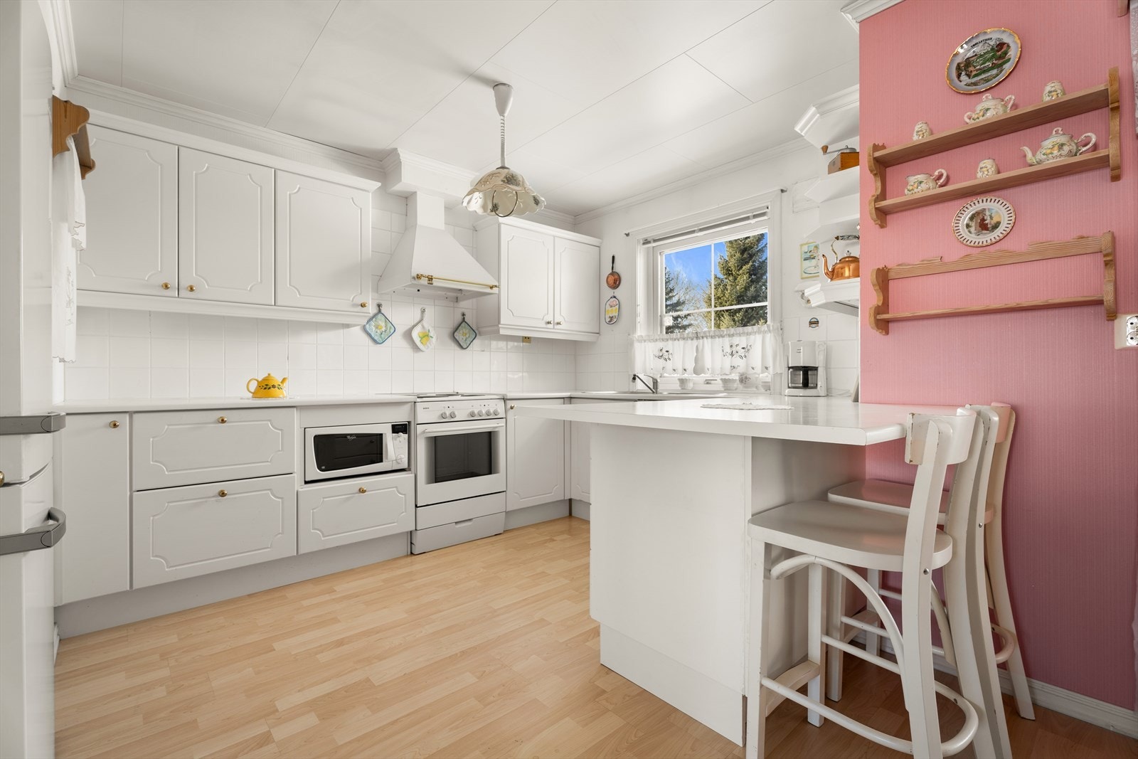 Kjøkkenet har hvite profilerte fronter og en praktisk barløsning. Galleribilde