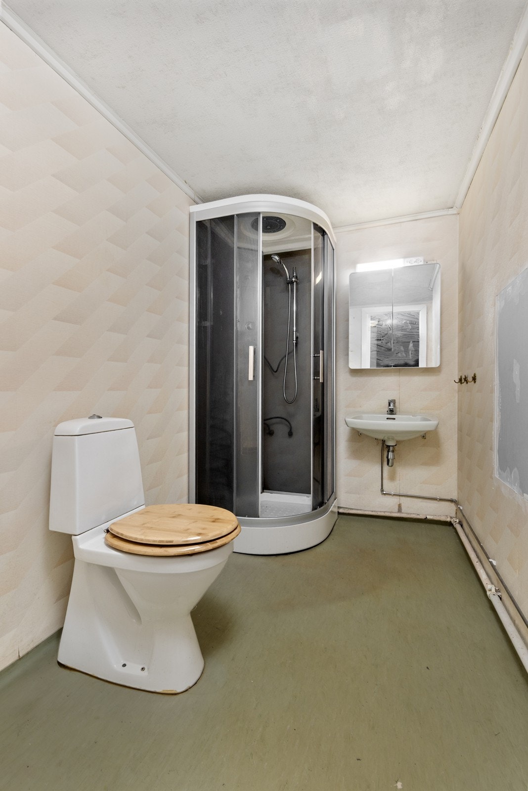 Badet har varmekabler i gulvet. Badet inneholder servantinnredning, toalett, dusjkabinett og opplegg for vaskemaskin. Galleribilde