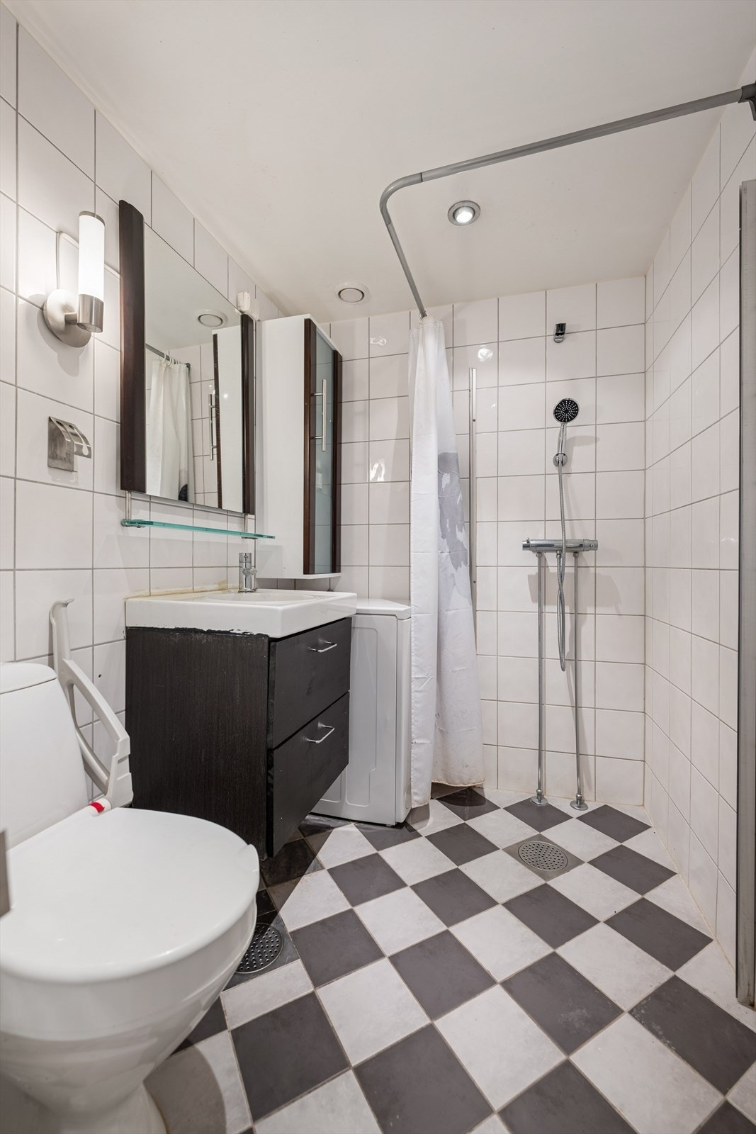 Flislagt baderom med behagelig gulvvarme. Badet er utstyrt med dusjhjørne, toalett, servant, speil og opplegg for vaskemaskin. Galleribilde