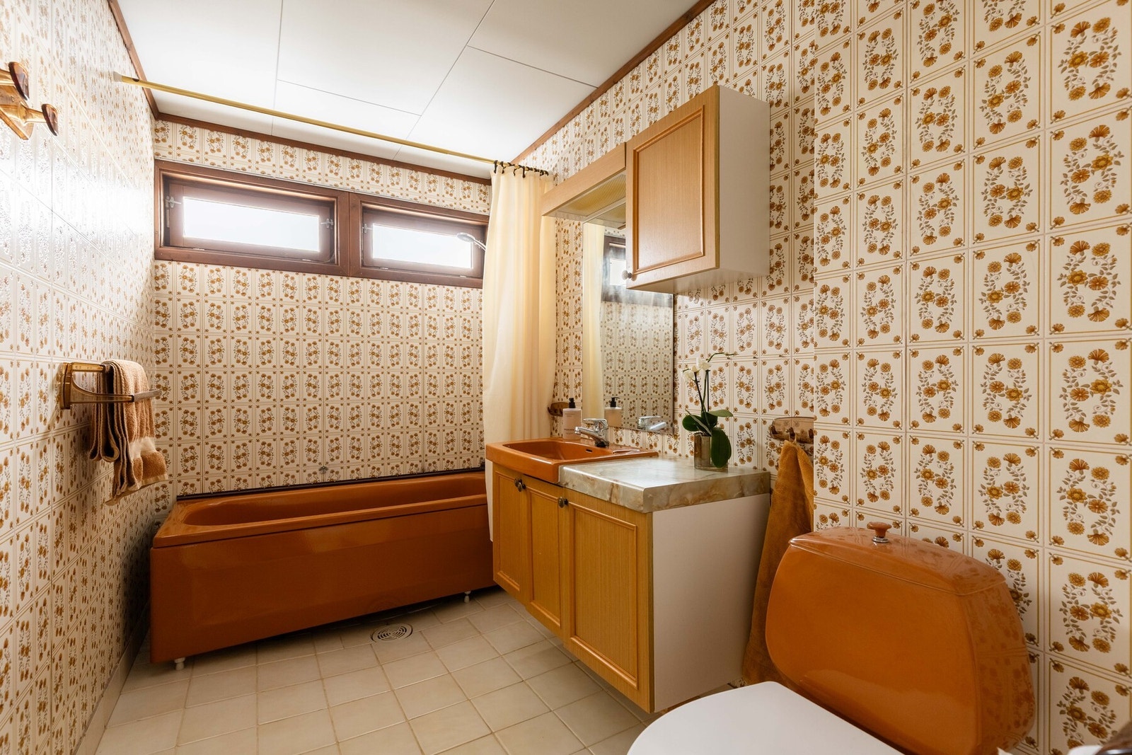 Baderommet er innredet med servant på innredning, speil med belysning, veggskap, toalett samt badekar med dusjarmatur. Badet er av eldre dato og har behov for oppgradering/modernisering. Galleribilde