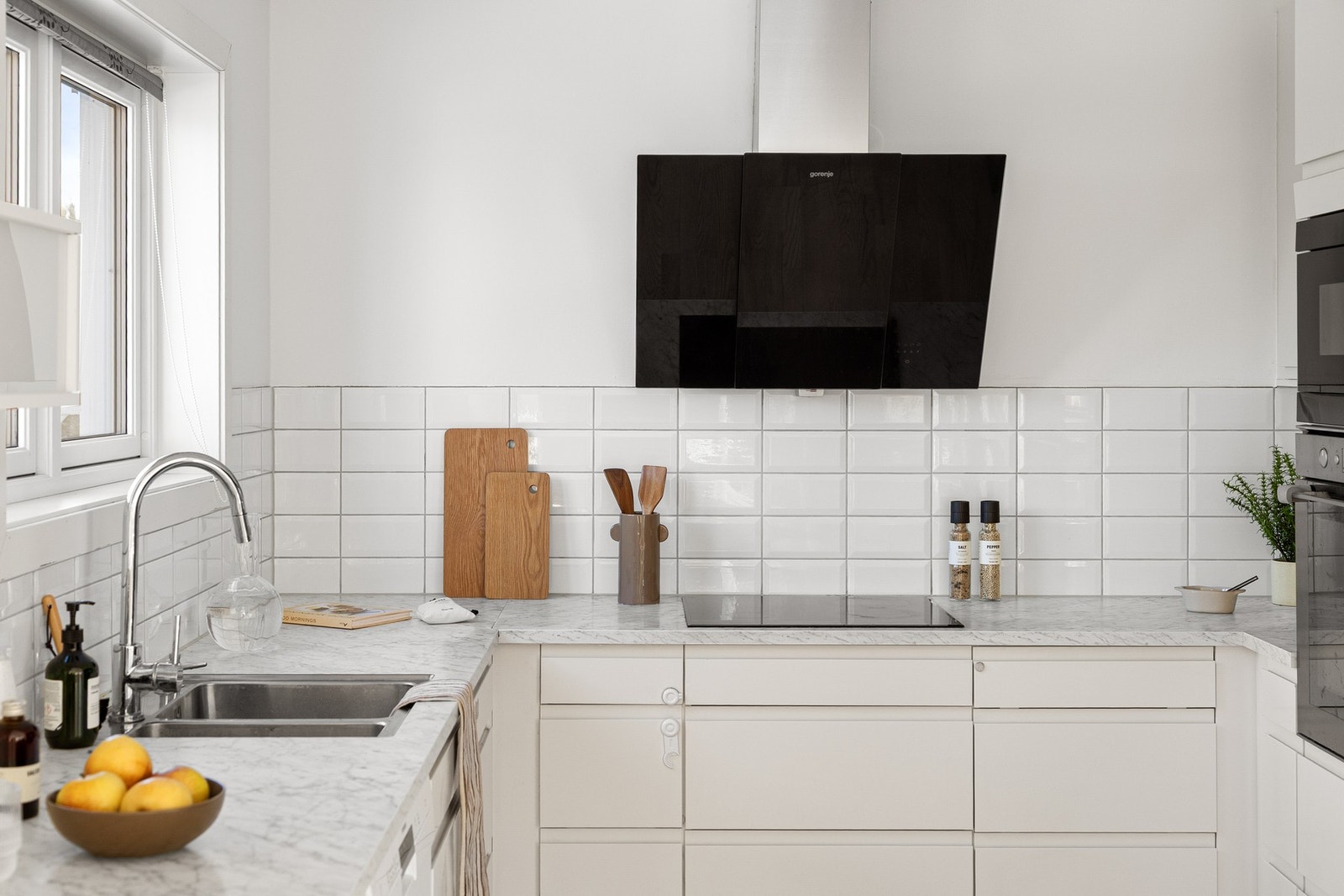 Lys innredning med benkeplate av laminat og dobbel oppvaskkum med ett-greps blandebatteri. På oversiden er det lagt flisfelt. Galleribilde