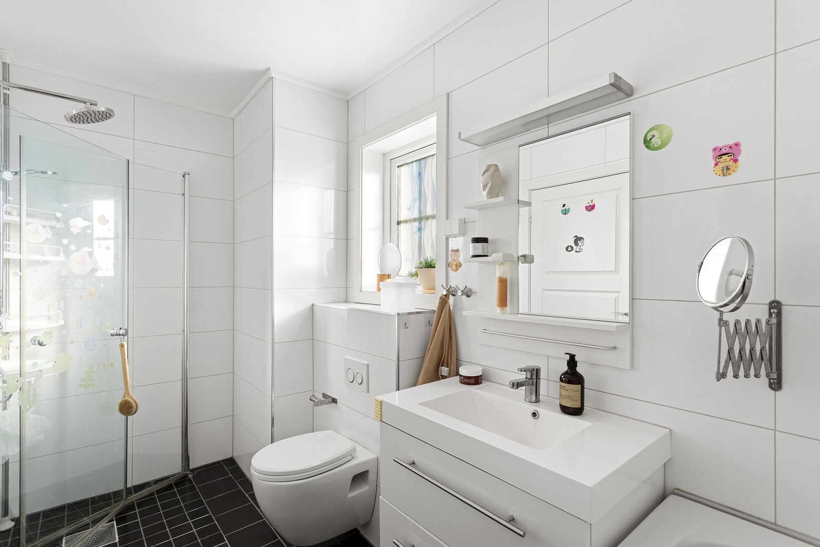 Midt i etasjen finner vi boligens familiebad. Badet er innredet med servant på underskuffer, speil og vegghengt toalett. Galleribilde