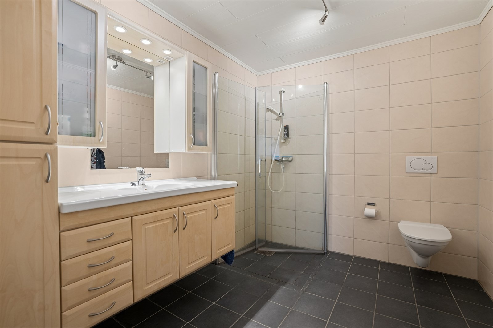 Romslig helfliset baderom med gulvvarme. Innredet med servant, skap, vegghengt toalett og innfellbare dusjvegger. Galleribilde