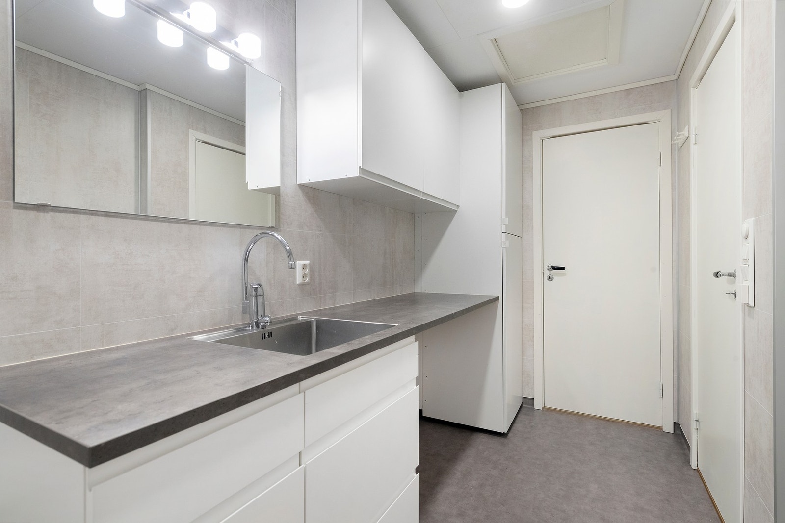 Bad/vaskerom innredet med nedfelt/utslaghsvask i stål, vegghengt toalett, dusjhjørne med glassvegger og opplegg for vaskemaskin og tørketrommel, samt godt med skapplass. Galleribilde