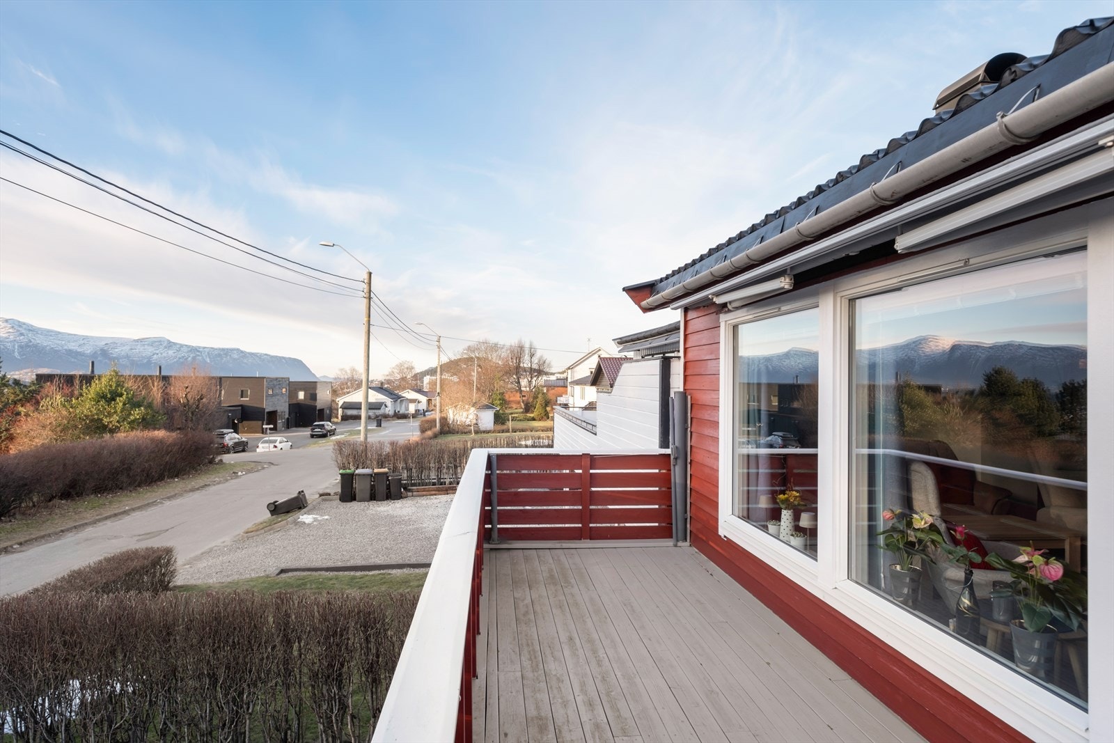 Utsikt fra balkongen mot nabolaget, med vinduer som gir lys inn i stuen. Galleribilde