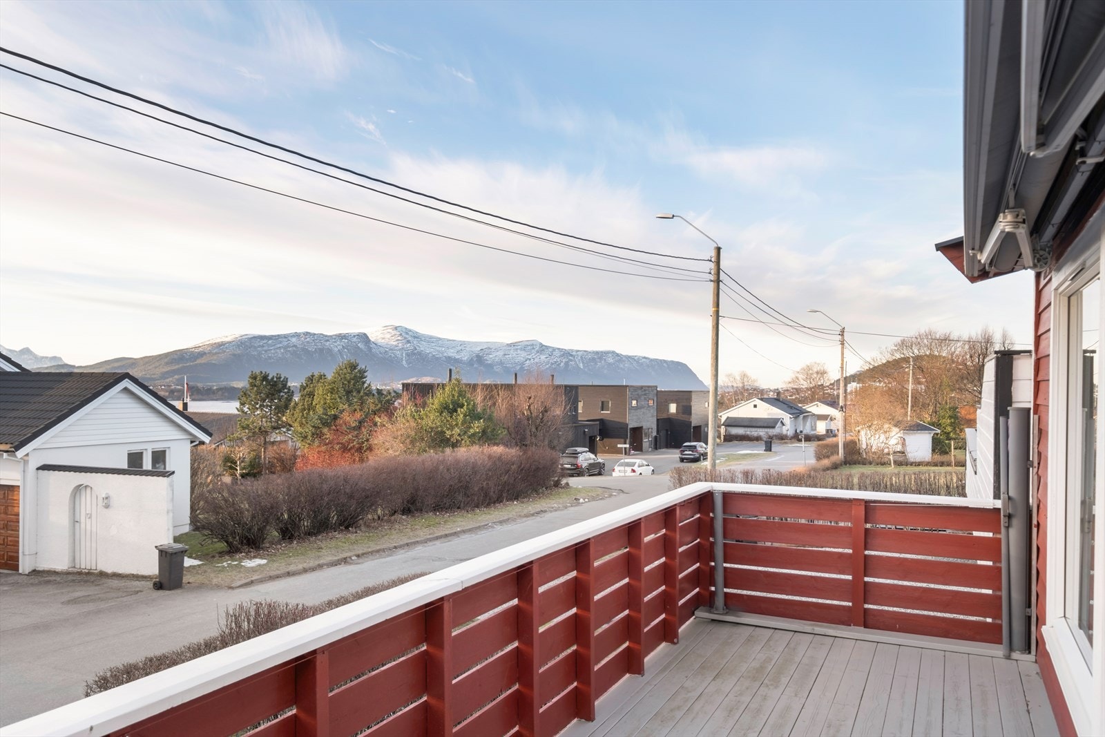 Balkongen gir utsikt mot fjellene og nabolaget, med rekkverk i tre som omkranser området. Galleribilde