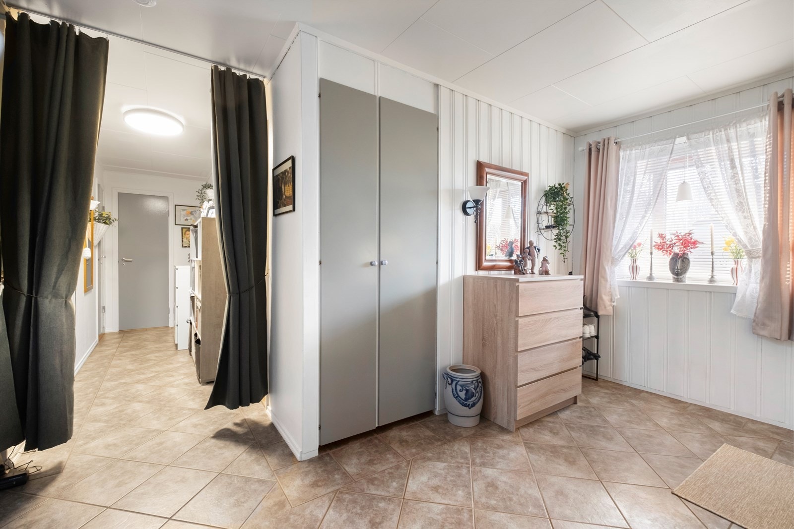 Flislagt gulv gir et praktisk og lettstelt inngangsparti. Skyvedørsgarderobe gir effektiv oppbevaringsløsning. Galleribilde