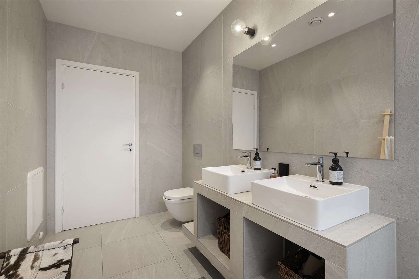 Rommet har et plassbygd og flislagt baderomsmøbel med to stilrene "bollevasker"/servanter, som gir både god funksjonalitet og et eksklusivt uttrykk. Speilet er limt direkte på flislagt vegg, med integrert belysning som gir behagelig og praktisk lys Galleribilde