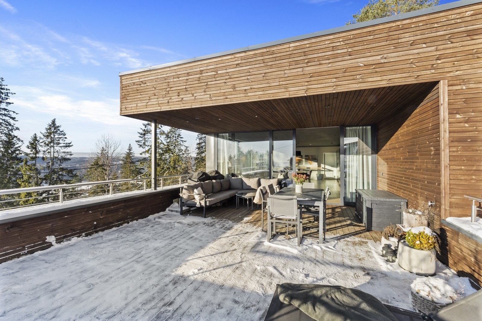 De store panoramavinduene og skyvedøren ut mot terrassen bidrar til at skillet mellom ute og inne viskes ut Galleribilde