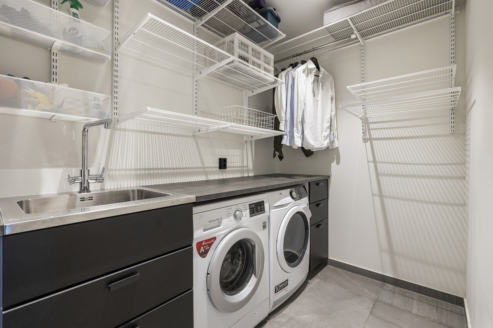 Vaskerom med utslagsvask og opplegg til vaskemaskin og tørketrommel. Flislagt gulv med varmekabler. Malte plater på vegger og i himling Galleribilde