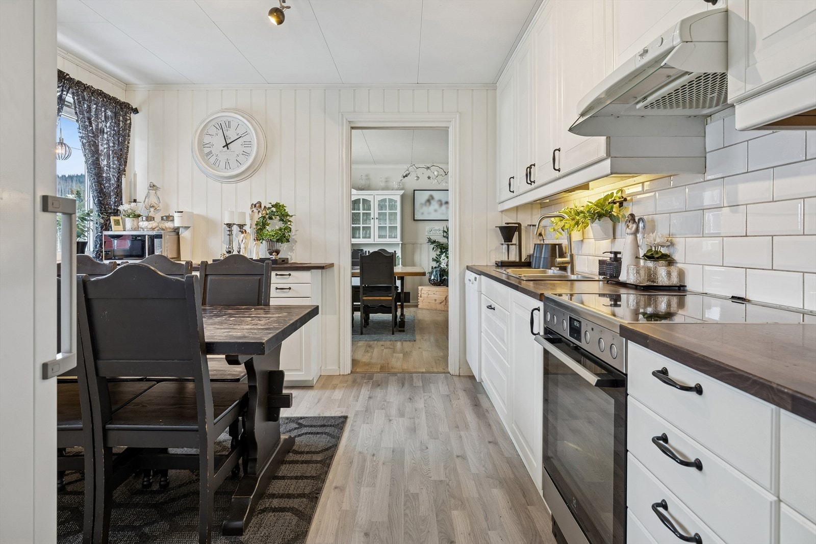 Kjøkkeninnredningen har lakkerte profilerte fronter, takhøye overskap og fliser over kjøkkenbenk. Galleribilde