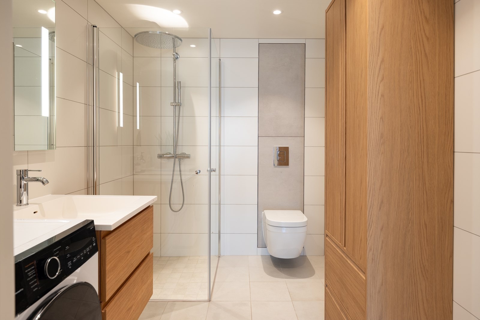 Flislagt bad med stilrene fargevalg. Lekre baderomsmøbler eik. Videre vegghengt toalett, dusjarmatur med dusjvegger og behagelig varme i gulv. Galleribilde