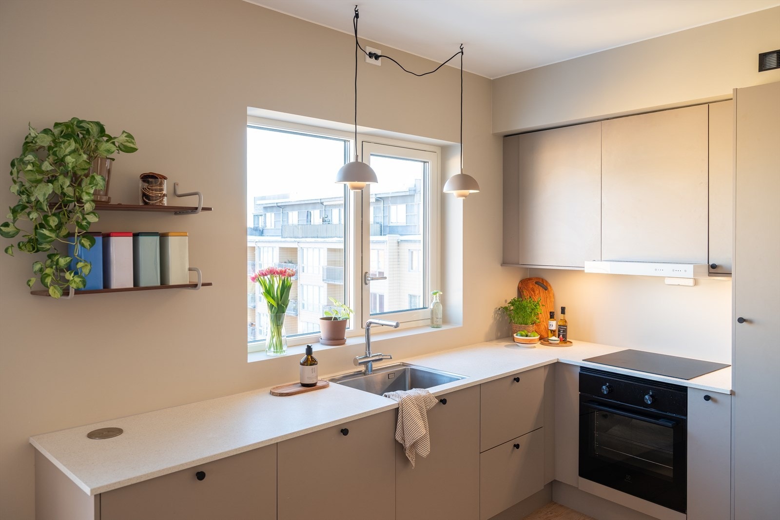 Tidløst kjøkken fra kvalitetesleverandøren HTH med L-form, hvit benkeplate og matte skap i sandfarget tone. Strømuttak med stikk og USB. Galleribilde