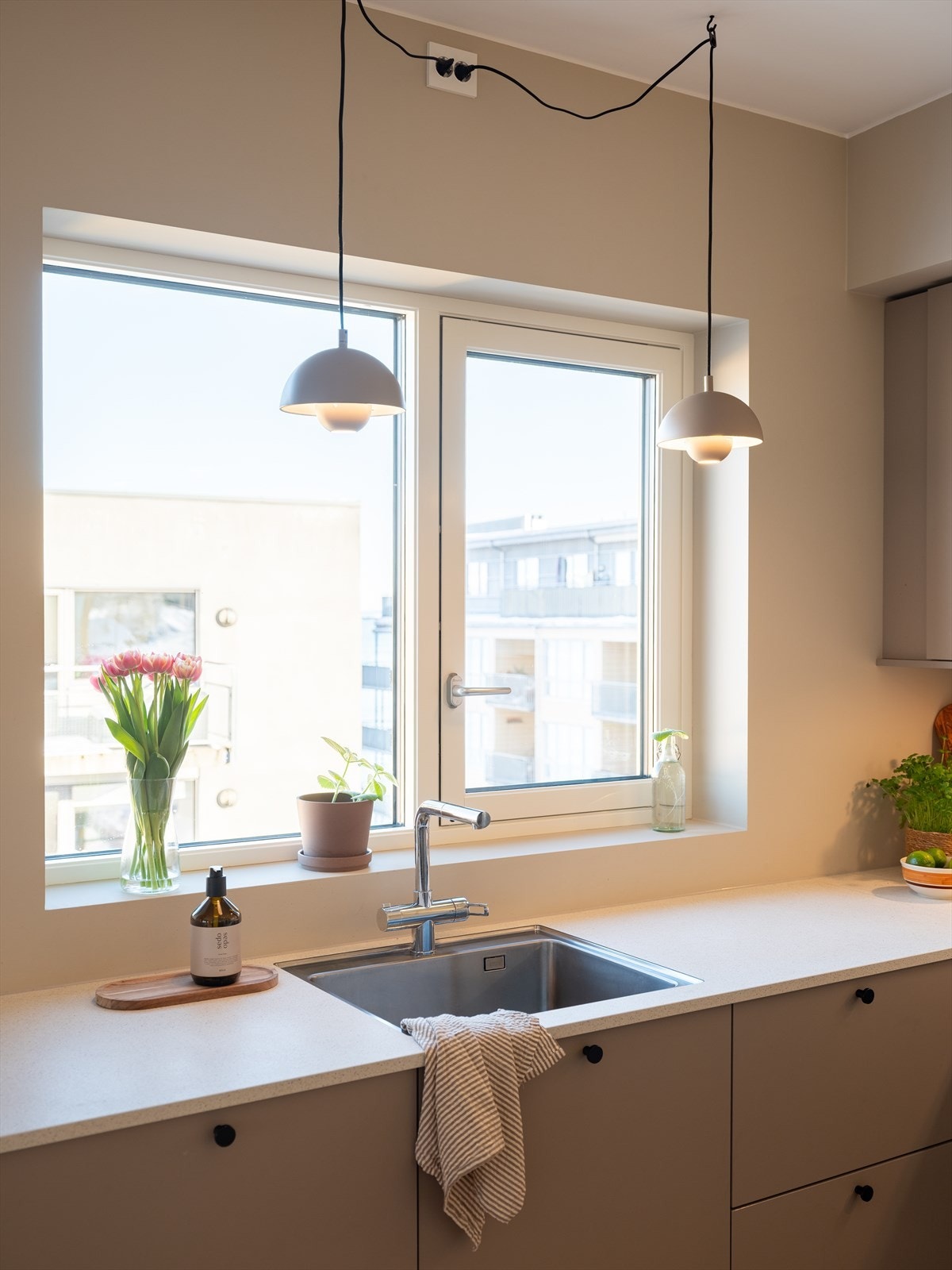 Kjøkkendetaljer med blandebatteri fra Tapwell med uttrekk, underlimt vask og god benkeplass på begge sider av vasken. Pendellys i par setter prikken over i-en. Et kjøkken som er like pent som det er praktisk. Galleribilde