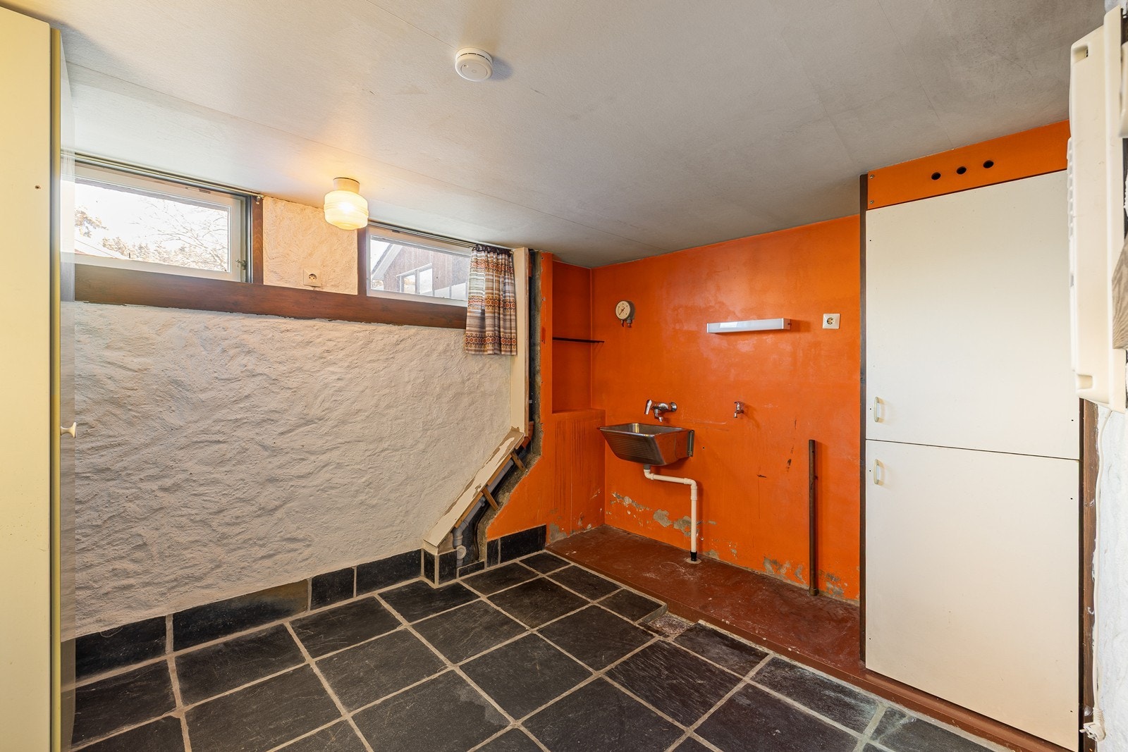 Boligen har et eldre vaskerom med fliser på gulv og tapetserte vegger. Innredningen består av et underskap/overskap og utslagsvask. Det er også opplegg for vaskemaskin Galleribilde