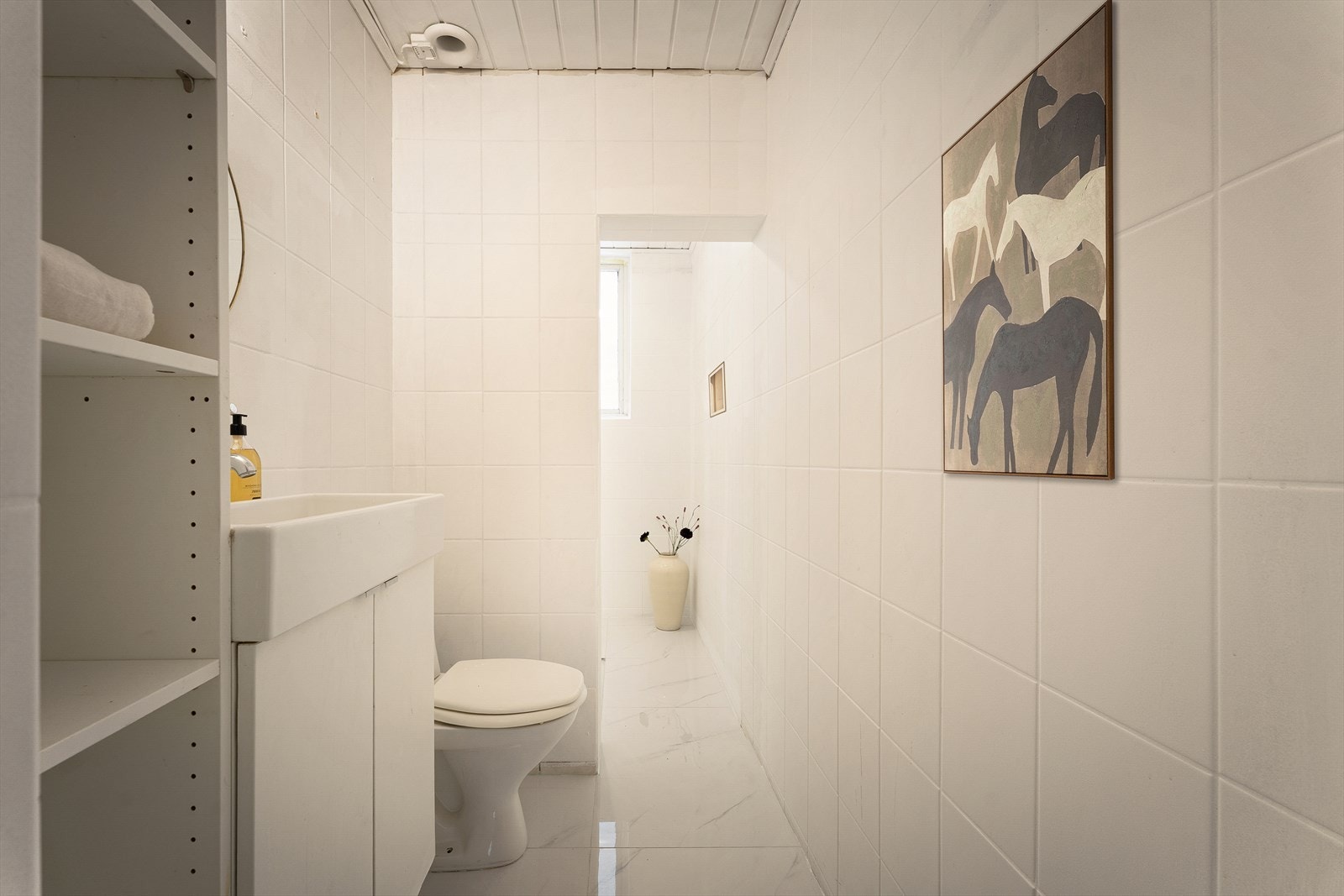 Det er lagt flis på flis på gulv i 2026 i følge eier. Baderomsinnredning bestående av benkeskap med glatte fronter. Dusj på gulv, servant og gulvstående klosett.
NB: Bildet er AI-redigert med bilder på vegg. Galleribilde