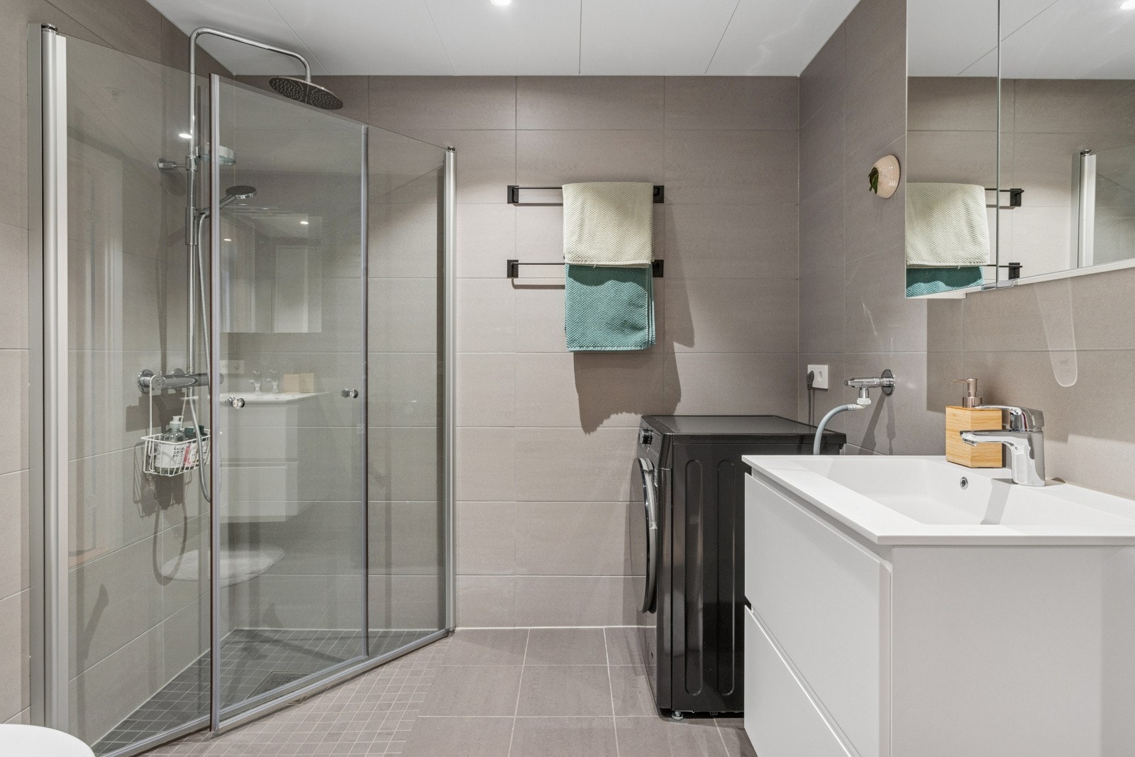 Badet har praktisk nedsenket dusjsone og opplegg for vaskemaskin Galleribilde