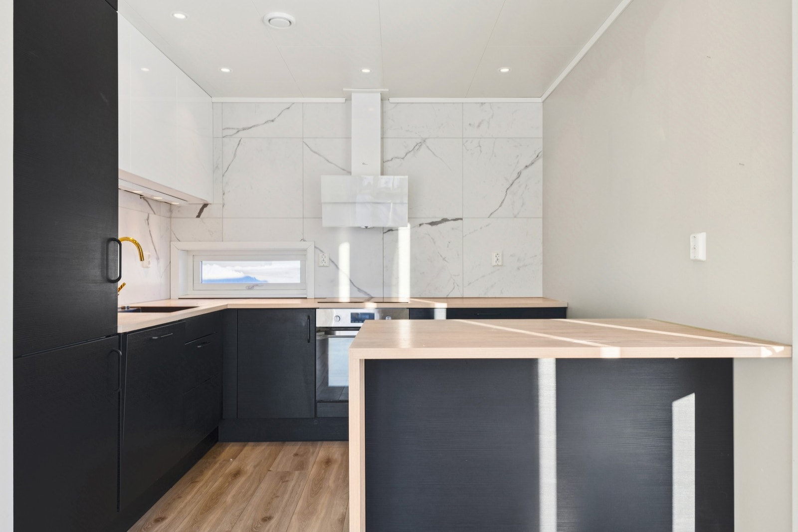 Stilrent kjøkken med en praktisk halvøy som gir ekstra benkeplass og en uformell spiseplass. Galleribilde