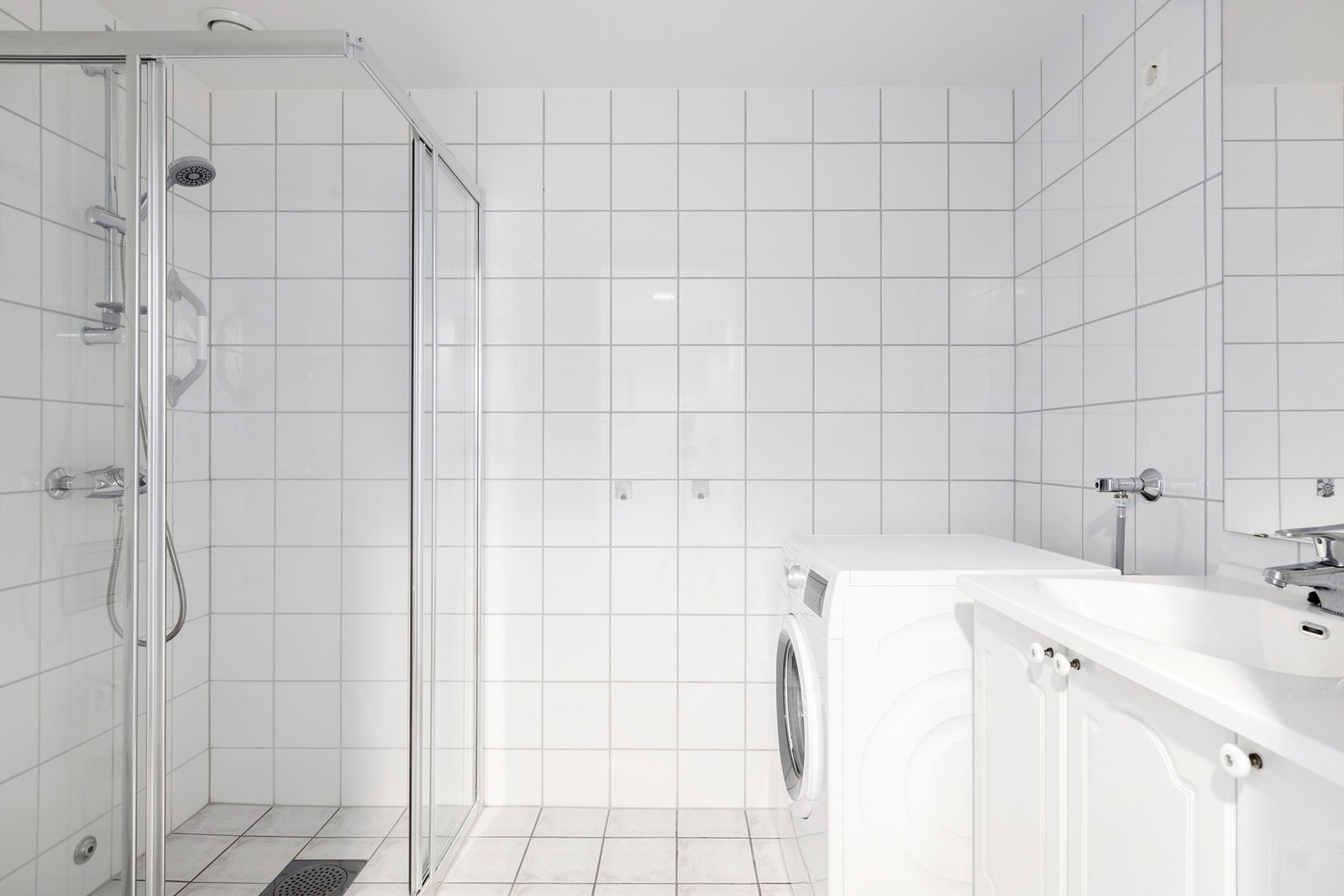 Badet er flislagt og har dusjhjørne med glassdører. Opplegg til vaskesøyle. Vegghengt toalett. Galleribilde