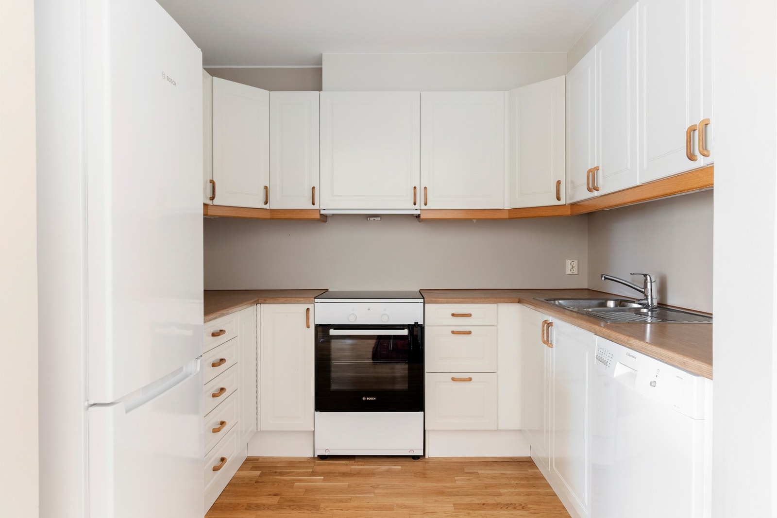 Kjøkkenet har hvit profilert innredning med svært mye skap og benkeplass. Frittstående hvitevarer. Galleribilde