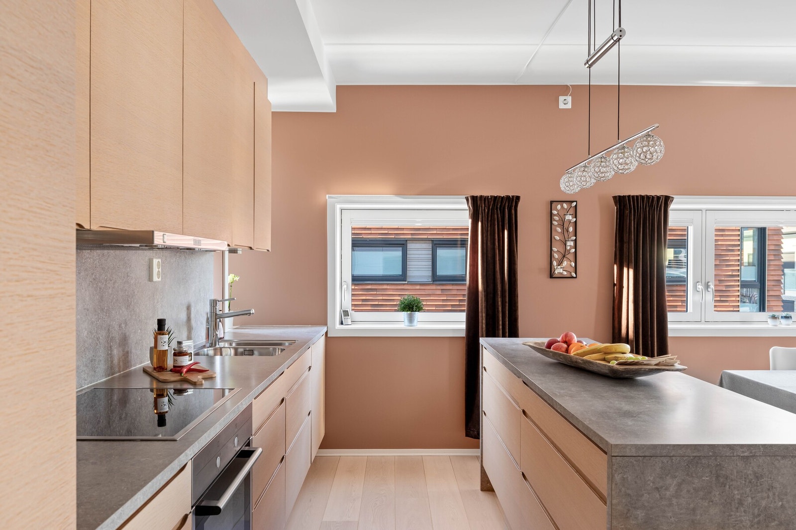 Innredningen har lyse, finerte fronter, takoppforede skap og grå laminatbenkeplate med planlimt kum i stål. Galleribilde